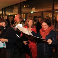 A group of people study the program of the market on large leaflets in the foyer of the Festpsiele.