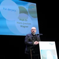 Prof. Dr. Hans-Joachim Wagner reads out a jury statement at the speaker's desk.