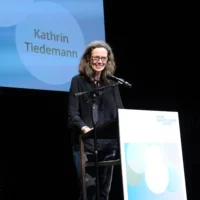 Katrin Tiedemann hält am Redner*innenpult die laudatio auf die Presiträger*innen Hofmann und Lindholm.