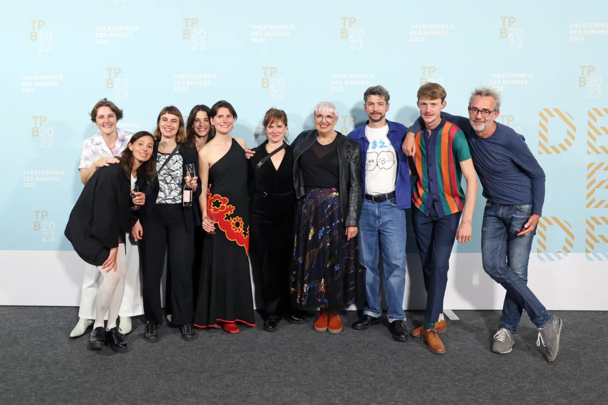 The team of Theaterhaus Jena with Minister of State for Culture Claudia Roth in front of a photo wall