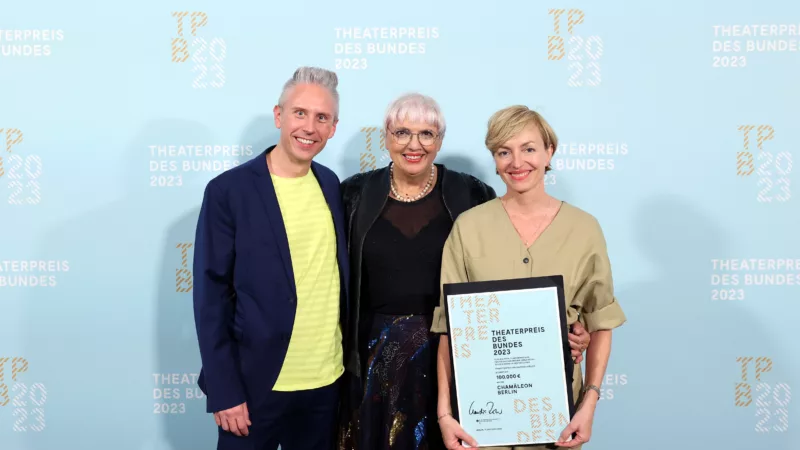 Hendrik Frobel (Management Chamäleon Theater), Claudia Roth (Minister of Culture), Anke Politz (Intendanz Chamäleon Theater) in front of a photo wall