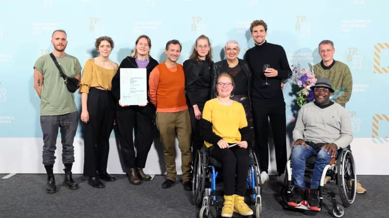 The team of LOFFT - Das Theater with Minister of State for Culture Claudia Roth in front of a photo wall