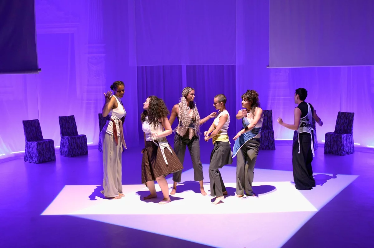 In einem rechteckigen Lichtfeld steht eine Gruppe von Frauen auf der Bühne. Sie tanzen jede für sich und doch miteinander.