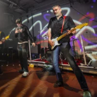 Konzert der Wolfener Punkband AbRAUM: auf der Bühne steht ein Sänger mit Sonnenbrille und Mikrofon in der Hand, links von ihm der Bassist der Band, rechts der Gitarrist.
