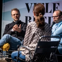 Jean Peters, Helge Lindh und Kathrin Tiedemann einander zugewandt im Gespräch. Kathrin Tiedemann sitzt mit dem Rücken zur Kamera.