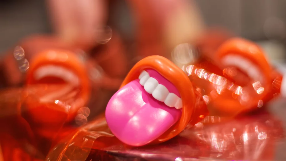 Das Bild zeigt ein auf einem Tisch liegendes Kunststoffobjekt in Form eines geöffneten Mundes mit rausgestreckter Zunge